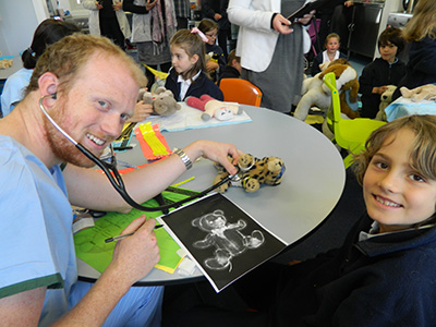 4th year medicine student Daniel DeWit checking the heart beat and discussing the outcome of the Teddy x-ray with a student.