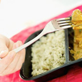 Hand with fork digging into food