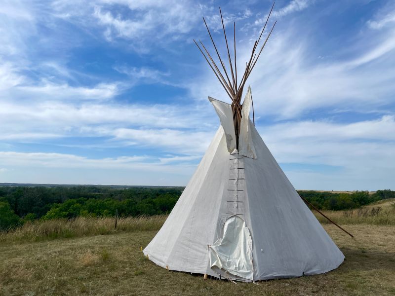 Large white tipi in a grassy plain.