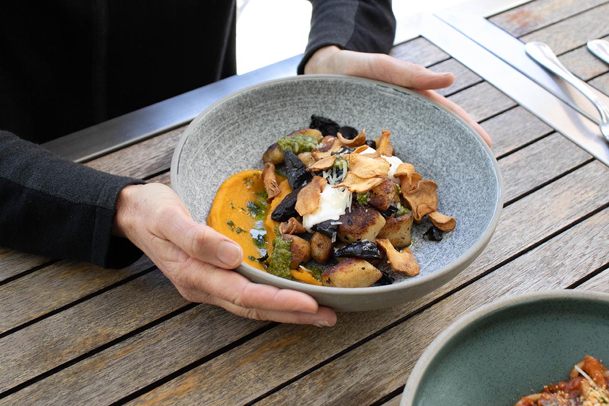 Hands holding a bowl of gnocchi