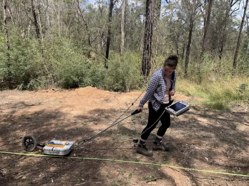 Woman in bushland pulling soil examining equipment