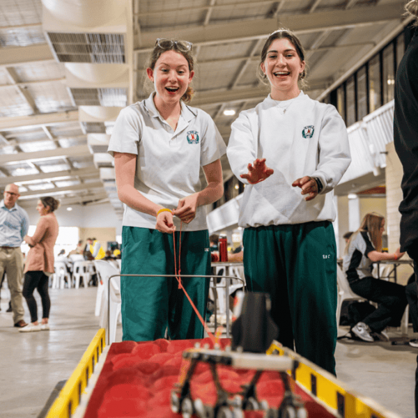 Two students pulling a Mars Rover model across a 'Mars surface'
