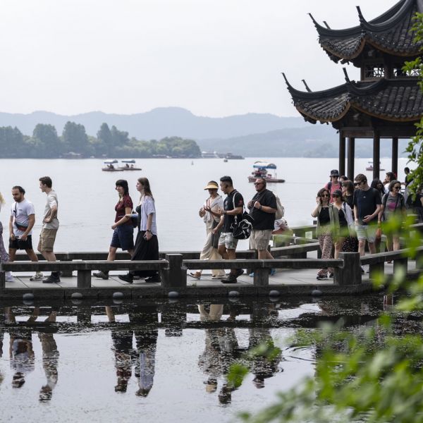 A group of University students and guides walking along the a bridge of the West Lake in Hangzhou, China.. Future leaders solving current problems 