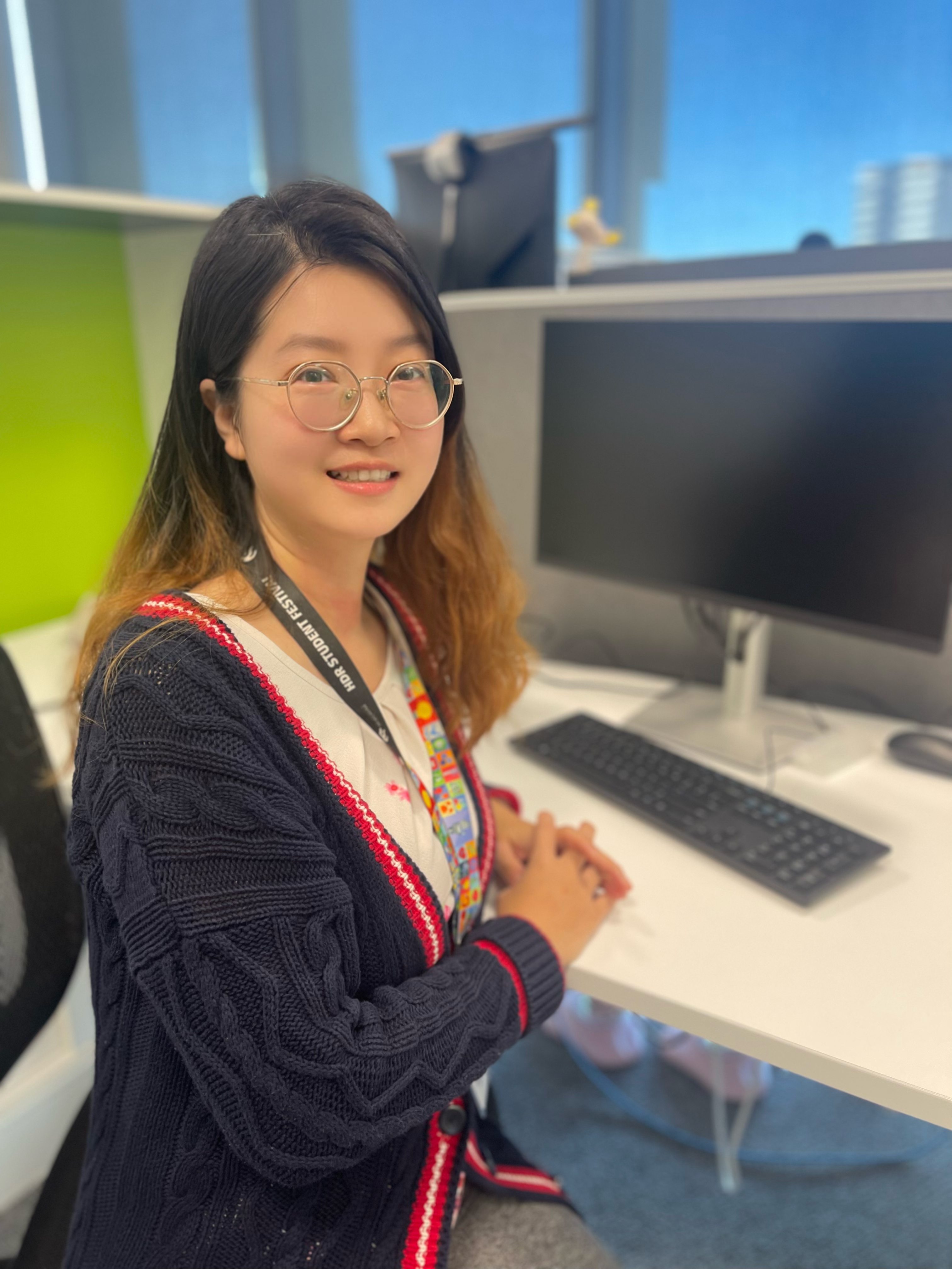 Yanjun (Michelle) Sui smiling at camera, sitting at Newcastle Business School HDR desk