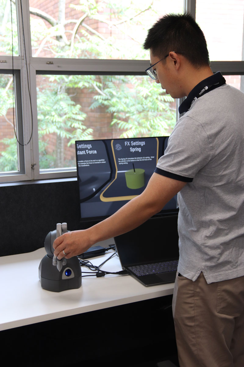 Academic staff member uses medical engineering equipment on a table in front of a computer