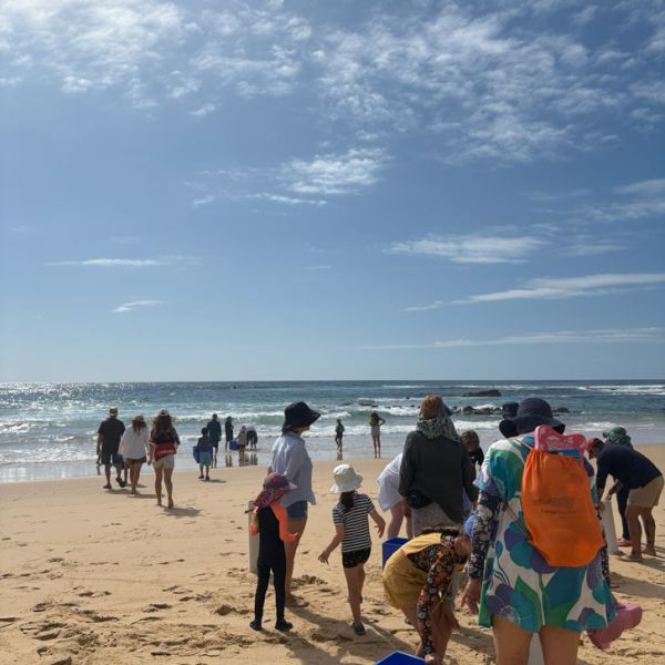 Community members standing on the beach. Families discover hidden coastal life through hands-on science workshops.