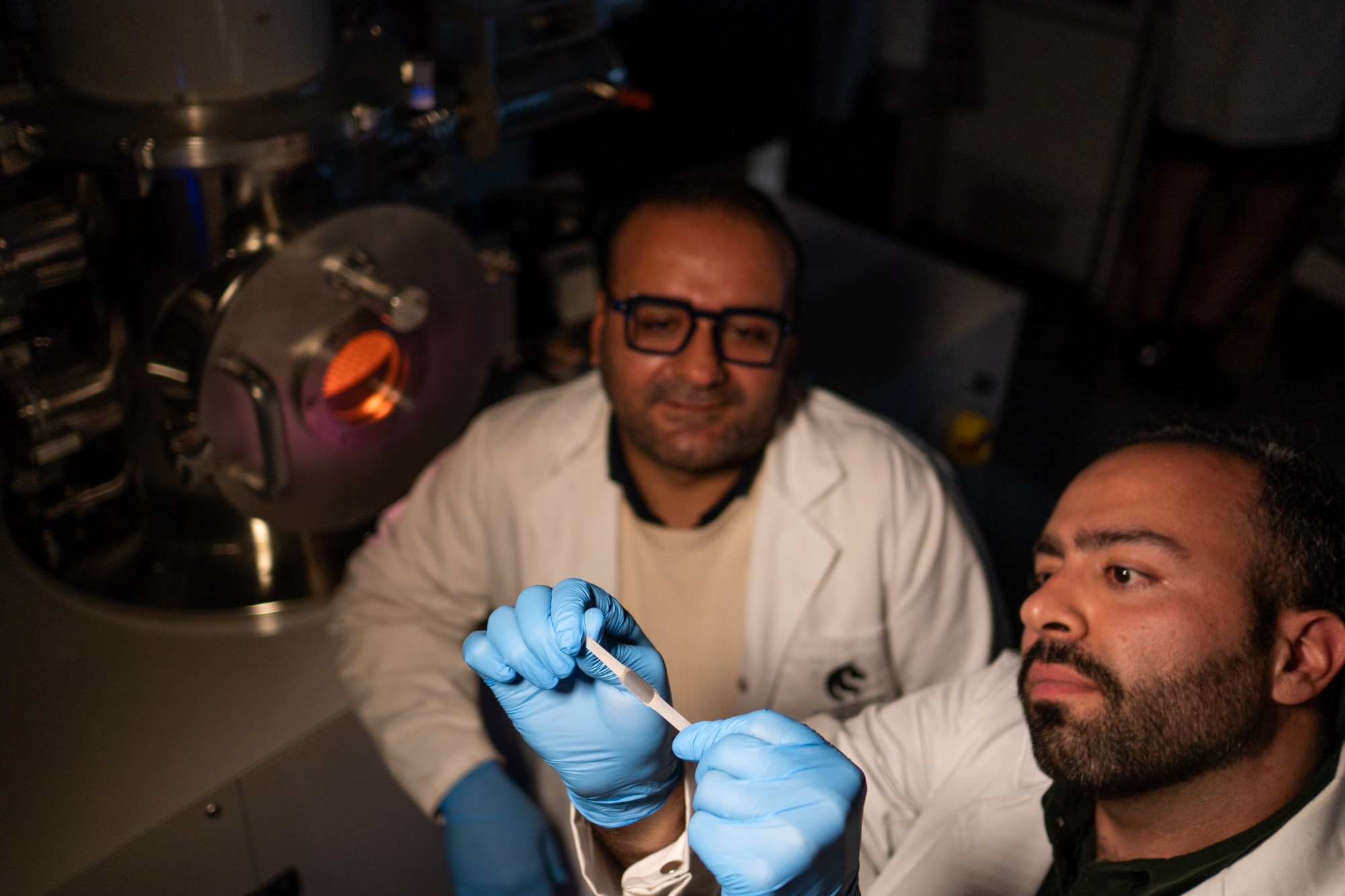 Associate Professor Behnam Akhavan and Dr Masoud Zhianmanesh researchers in a lab holding up a clear polymer strip and stretching it