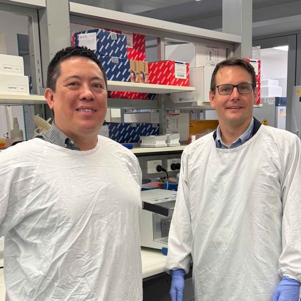 Two researchers, Professor Simon Keely and Associate Professor Gerard Kaiko, wearing white laboratory gowns stand beside a lab bench in a research laboratory.. World-leading study uncovers new targets for inflammatory bowel disease treatment