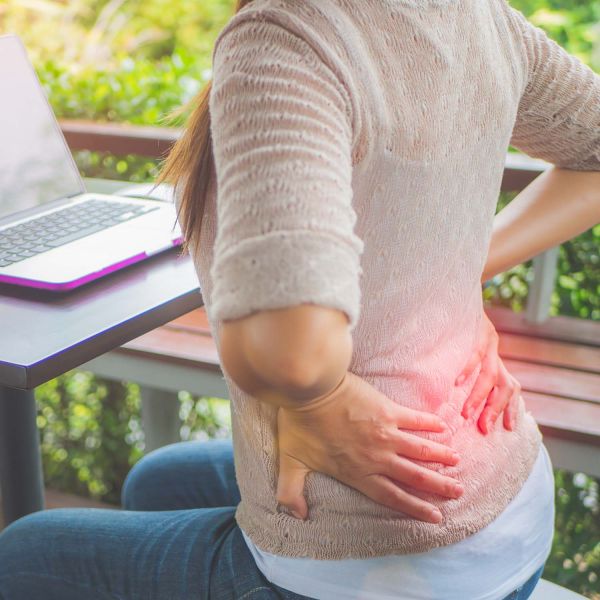 Young woman sitting with back pain. Teen back pain linked to substance use