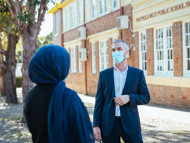 Principal Matthew Bradley faces the camera and Laila back of head outside Mayfield West school