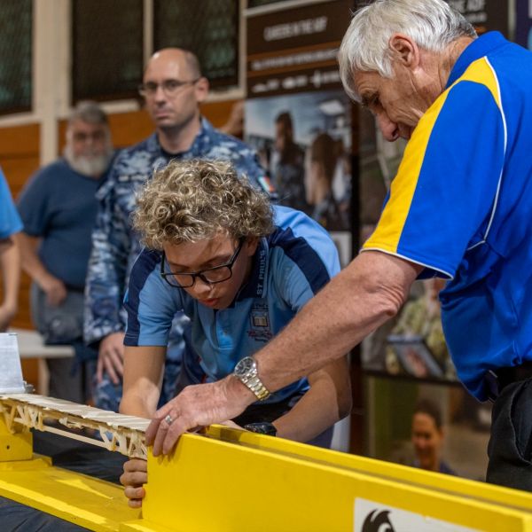 A high school student and staff member work together in the bridge building challenge