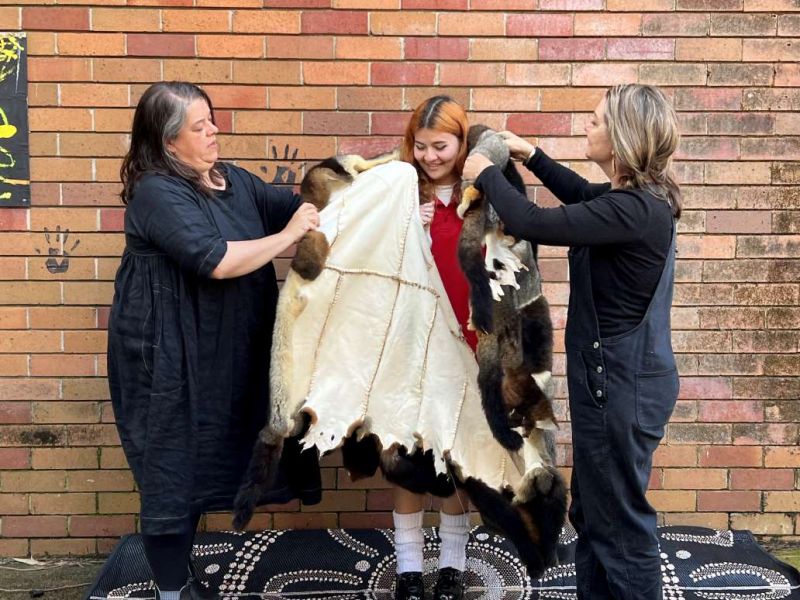 A high school student being wrapped in a possum skin cloak