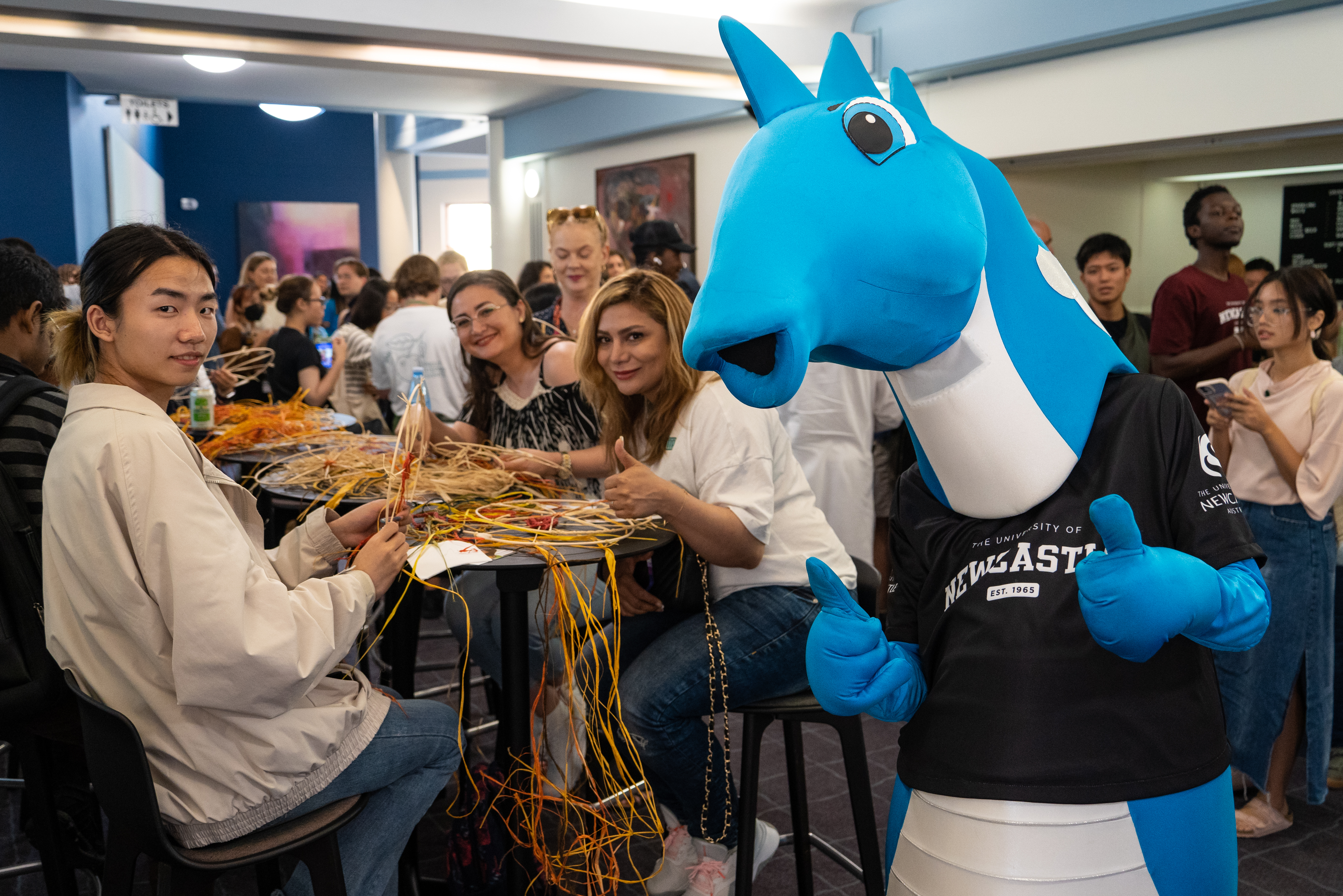International students work on weaving project with the University mascot Hunter the Hippocampus