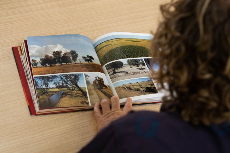 An over-the-shoulder photo of Anthony reading a book with photos of drought-stricken land juxtaposed with green pastures