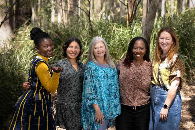 Three UNESCO Chair scholars stand with Prof Penny Jane Burke and Dr Gifty Gyamera amongst the trees on camous