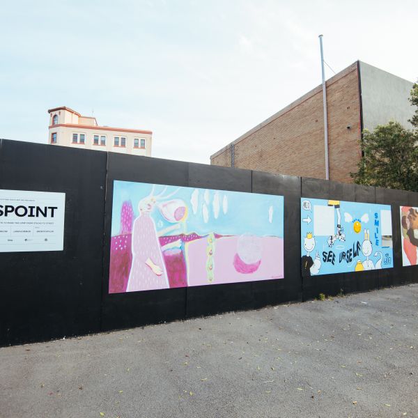 Wide shot of 4 murals painted along a black wall