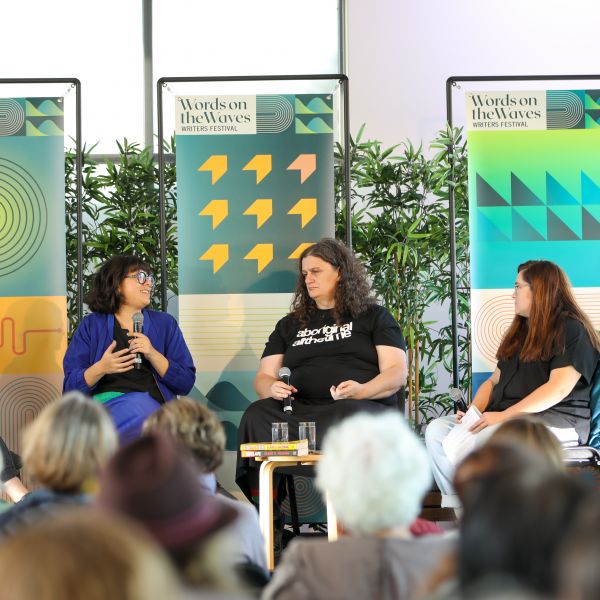A four person panel with microphones sitting down on stage, with one person talking