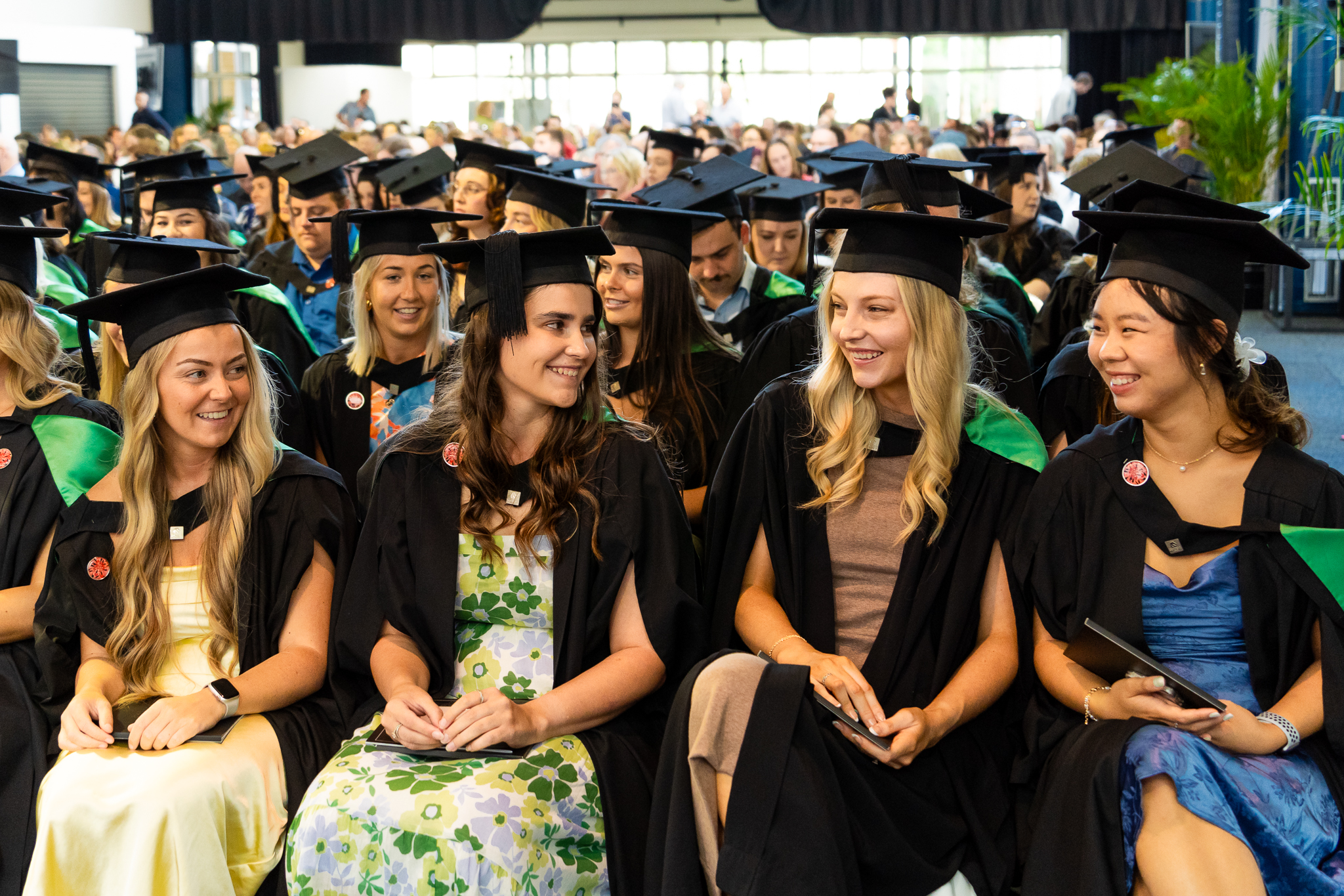A row of graduates smiling as they wait for the ceremony to begin