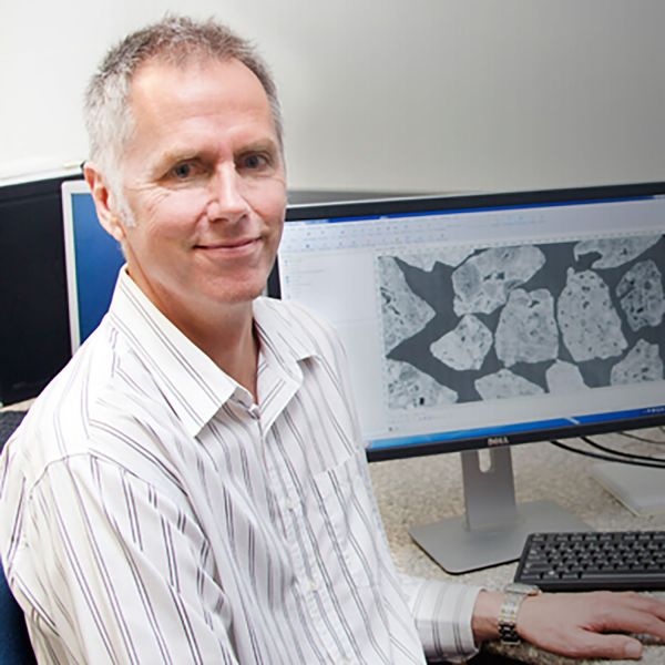 Professor Tom Honeyands smiling to camera at his desk researching 