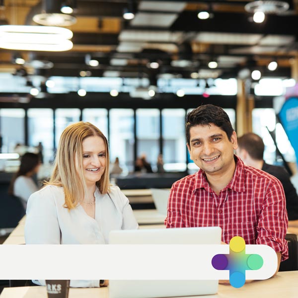 Two students chatting and working on a laptop