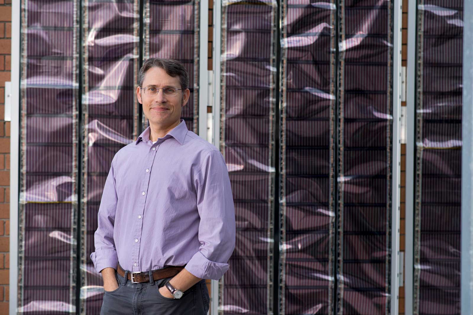 Professor Paul Dastoor is the inventor of Printed Solar.  Professor Paul Dastoor standing in front of a backdrop of Printed Solar.