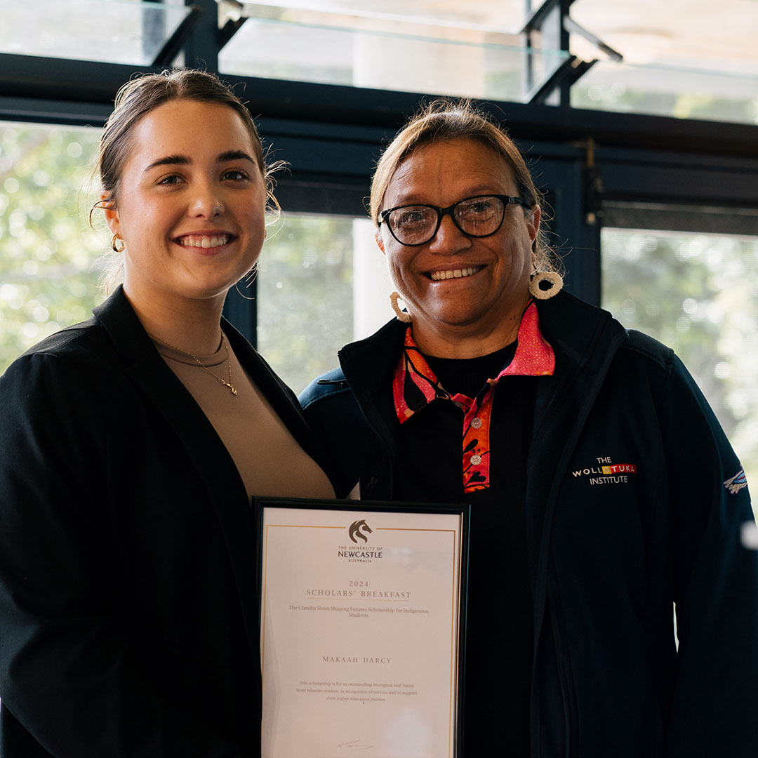Two women standing side by side with one holding a certificate