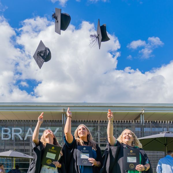 Graduates celebrate and throw their caps into the sky. Skilled.