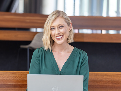 A woman sitting at a desk with a laptop smiling