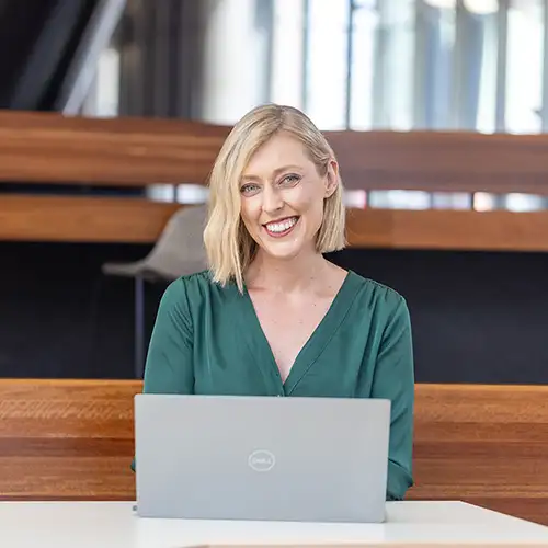 A woman sitting at a desk with a laptop smiling