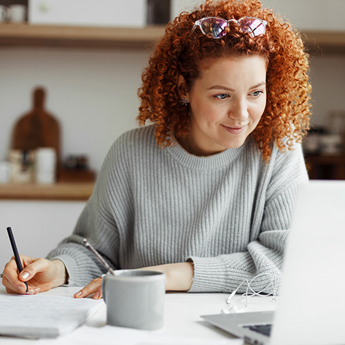 A women sitting at a desk writing on a notepad