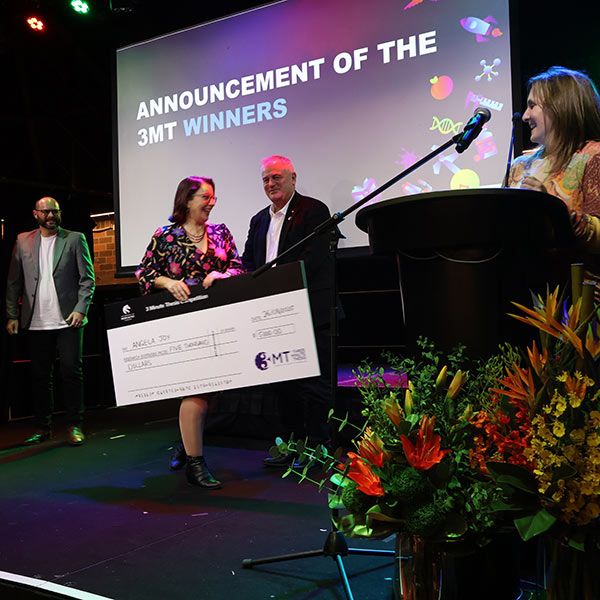 Women receive novely cheque prize on stage surrounded by judges. Research that resonates: PhD candidates shine in festival competition.
