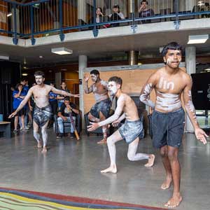 Four people are dancing with white ochre body paint and black shorts