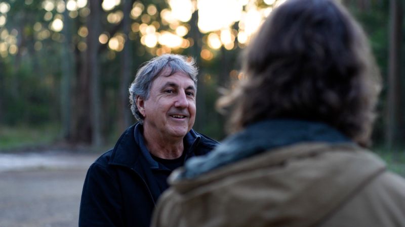 Daryn McKenny pictured chatting to someone as the sun sets against a bush backdrop