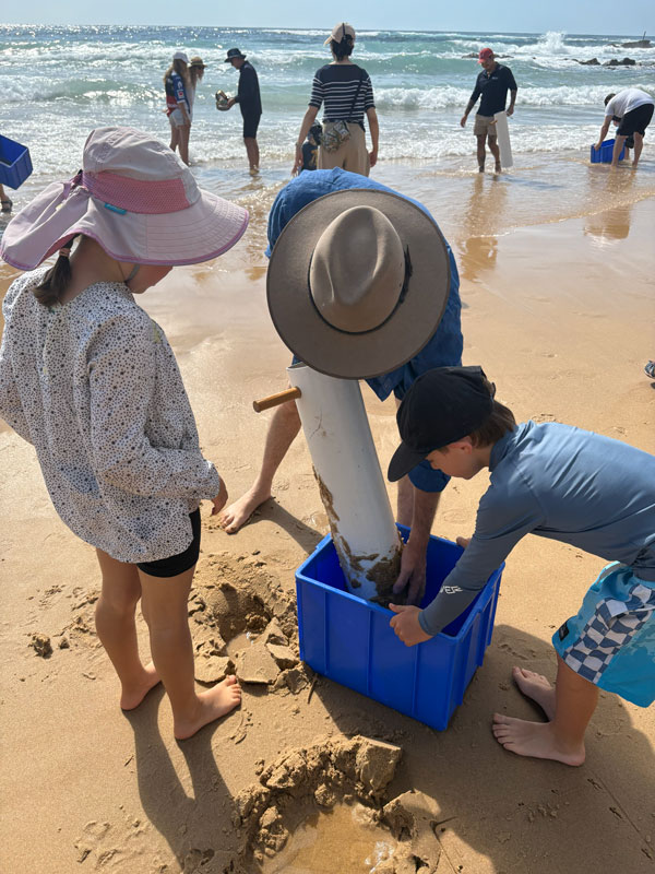 Community members put sand into a blue tub