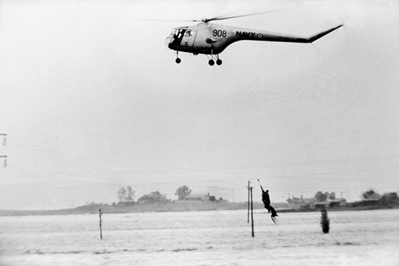 A helicopter hovering over a flooded Maitland suburb to rescue residents trapped by the 1955 flood.