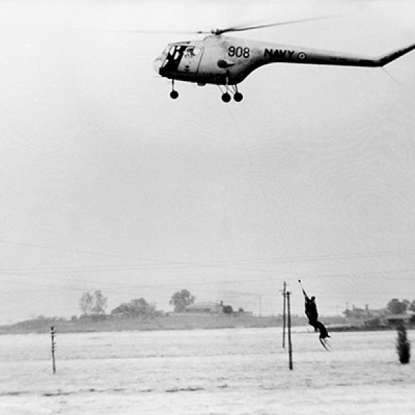 A helicopter hovering over a flooded Maitland suburb to rescue residents trapped by the 1955 flood.