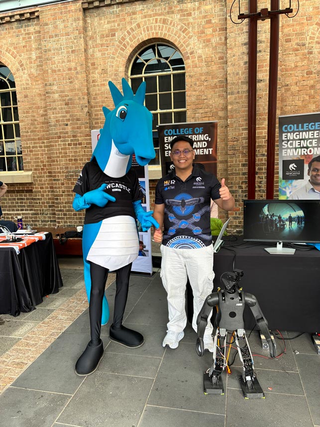 Hunter mascot standing with NUbots team member and robot