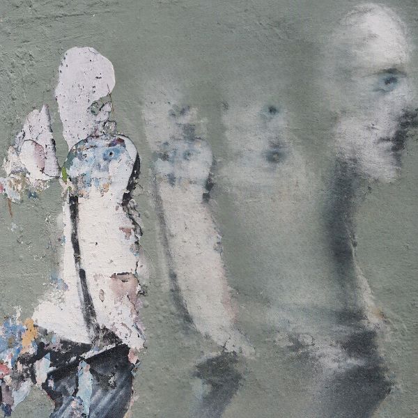 A weathered wall features a faded mural of several ghostly human silhouettes and a partially visible face, with peeling paint and textured surfaces creating a distressed, urban-art appearance.