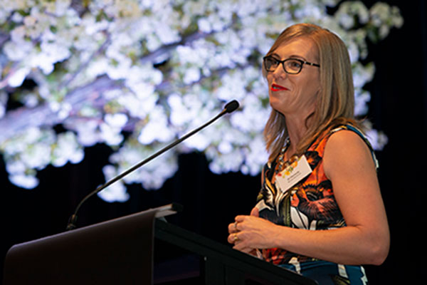 Image of a woman speaking in front of a crowd