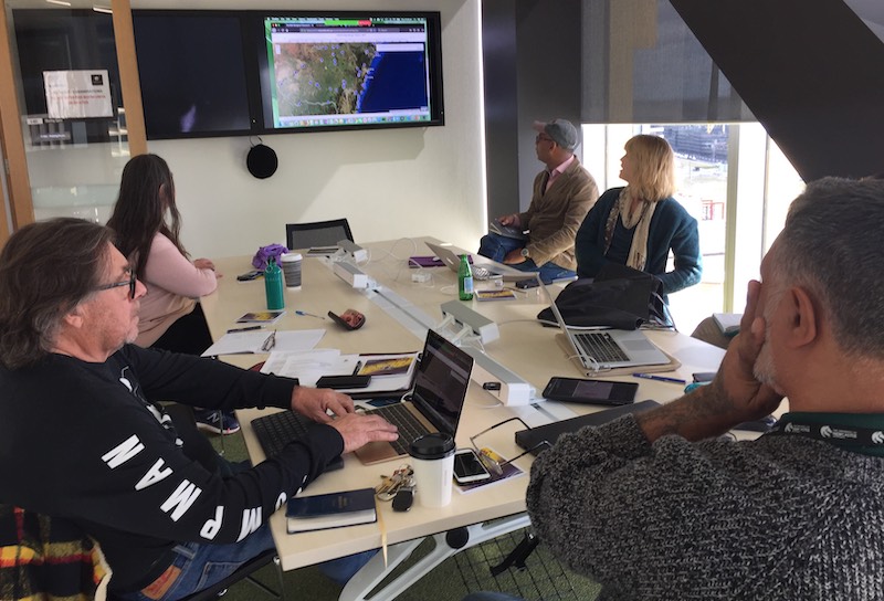 People sitting around a table looking at a projected digital map