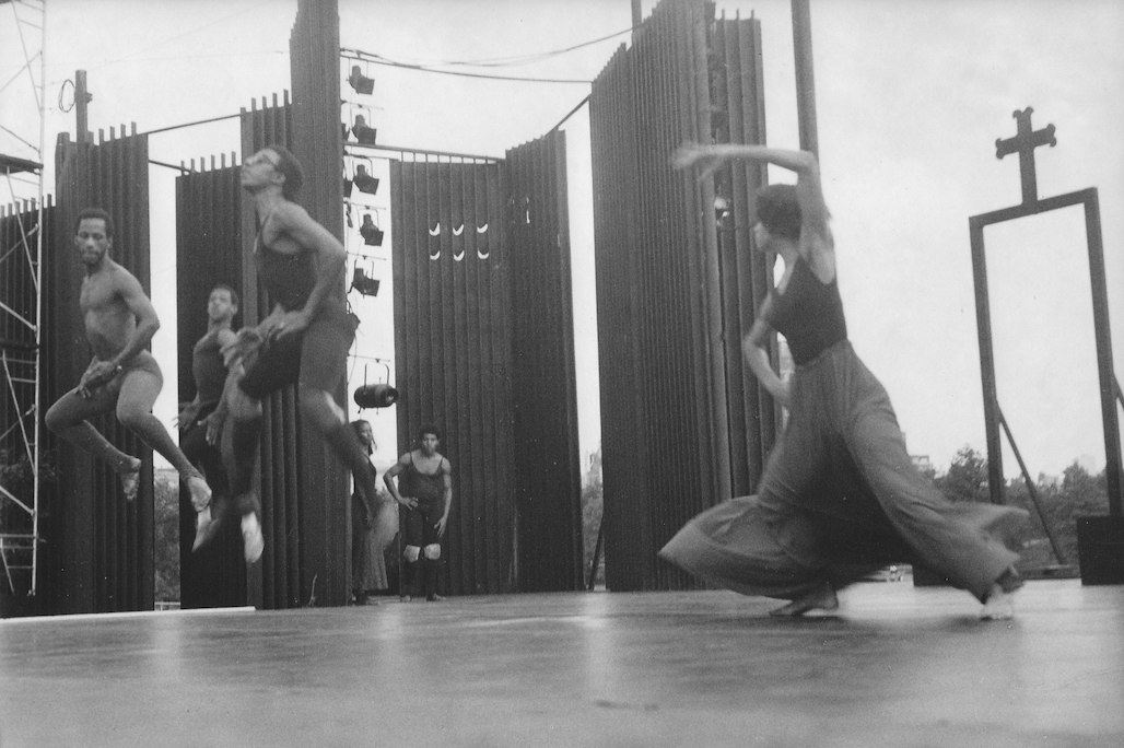 Four dancers leaping into the air and performing on an outdoor stage