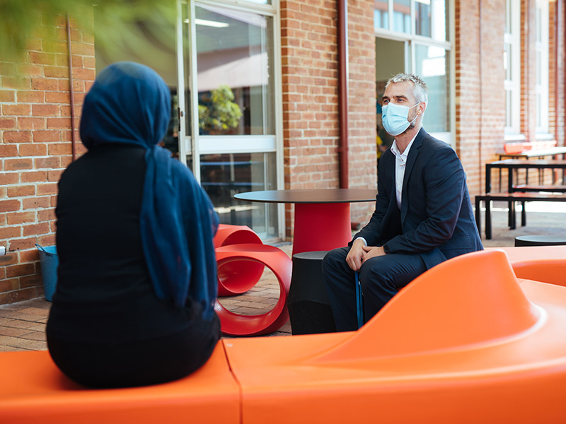 Back of Laila as she faces Principal Bradley talking on a bench