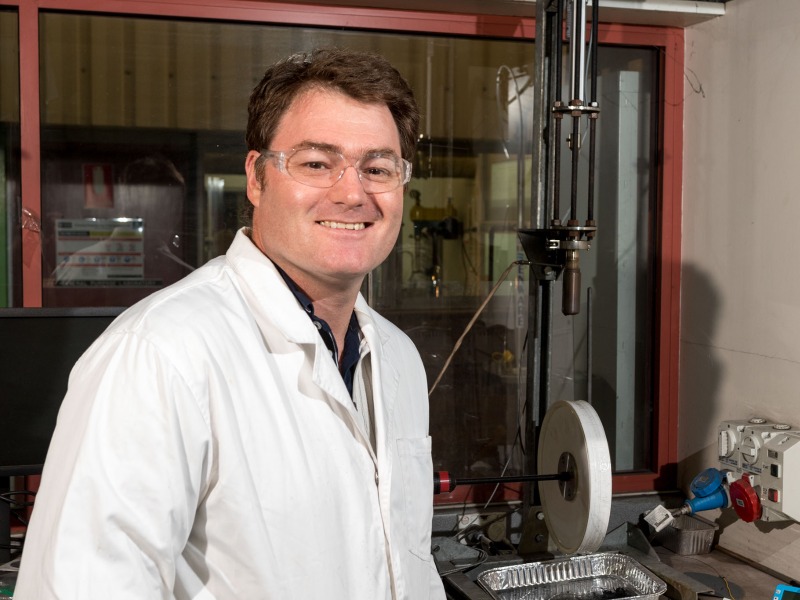 Rohan Stanger in a lab wearing a lab coat and glasses