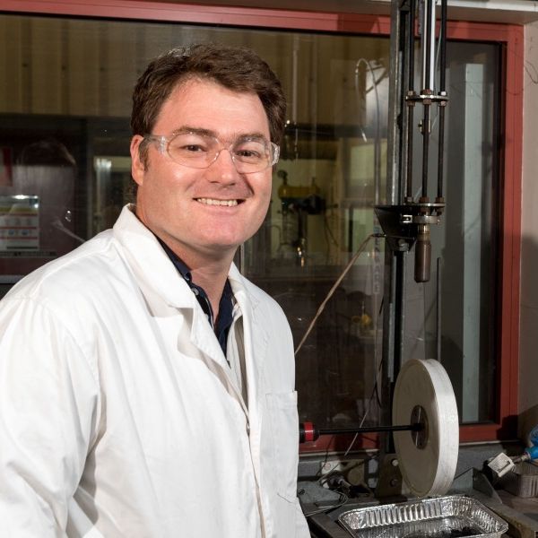 Rohan Stanger in a lab wearing a lab coat and glasses
