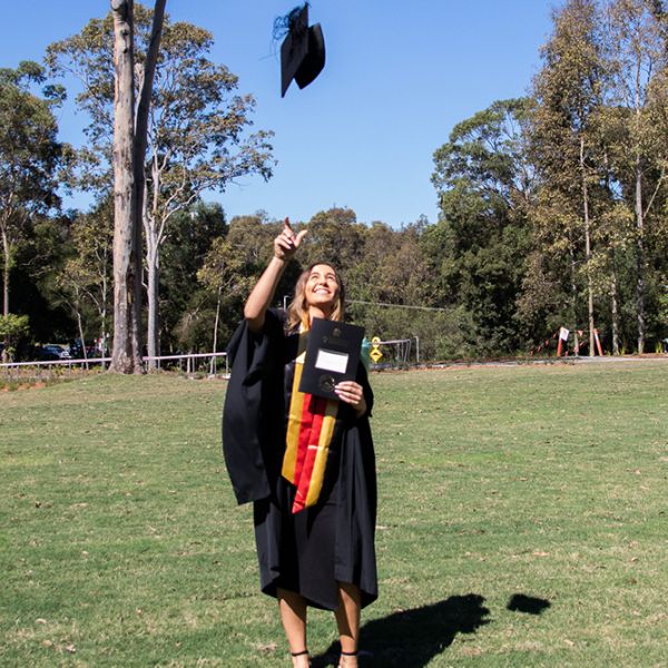 Graduate throws hat in the air. University of Newcastle tips hats to latest cohort of graduates .