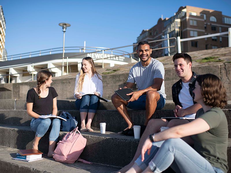 A group of students sitting on the stairs at Newcastle Beach