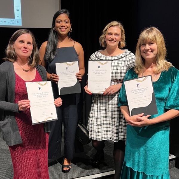 Four beautiful women in formal dress holding award certificates and smiling. A trove of extraordinary stories: Collaborative project wins top multicultural history award 