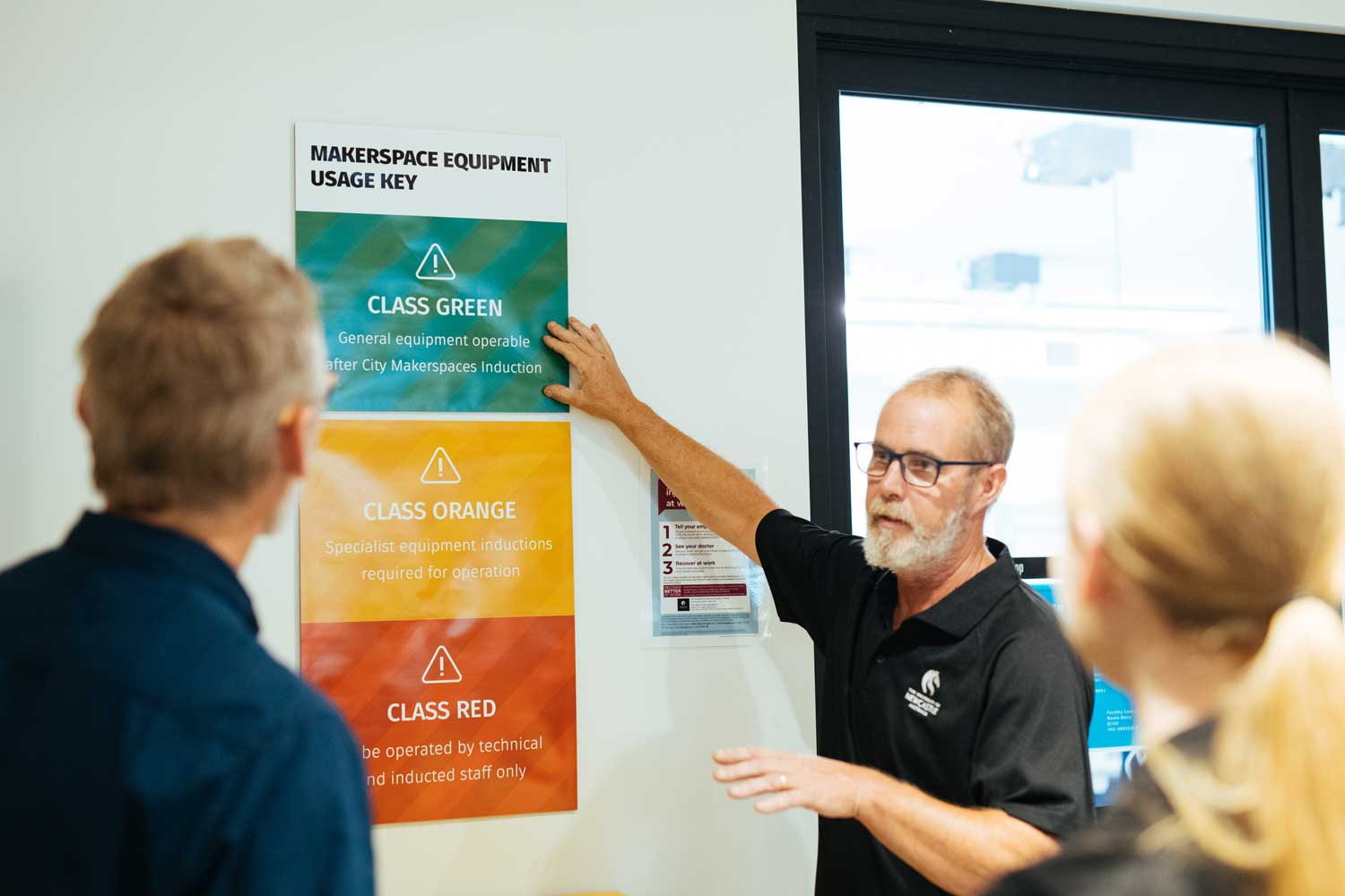 Staff member conducting a safety induction - pointing to a poster showcasing hazard levels.