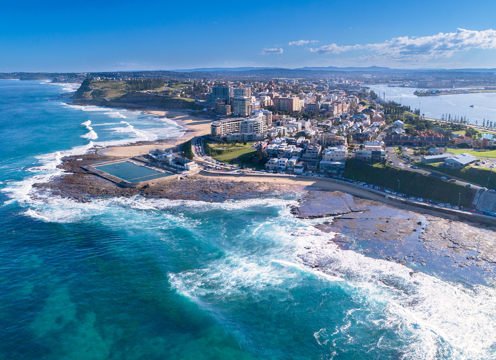 Aerial photo from the ocean looking back on Newcastle Ocean baths and over to the harbour