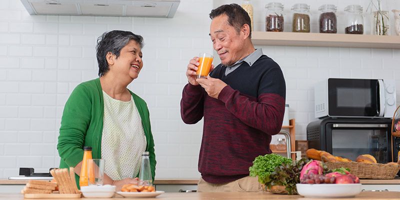 Couple standing in kitchen drinking juice 